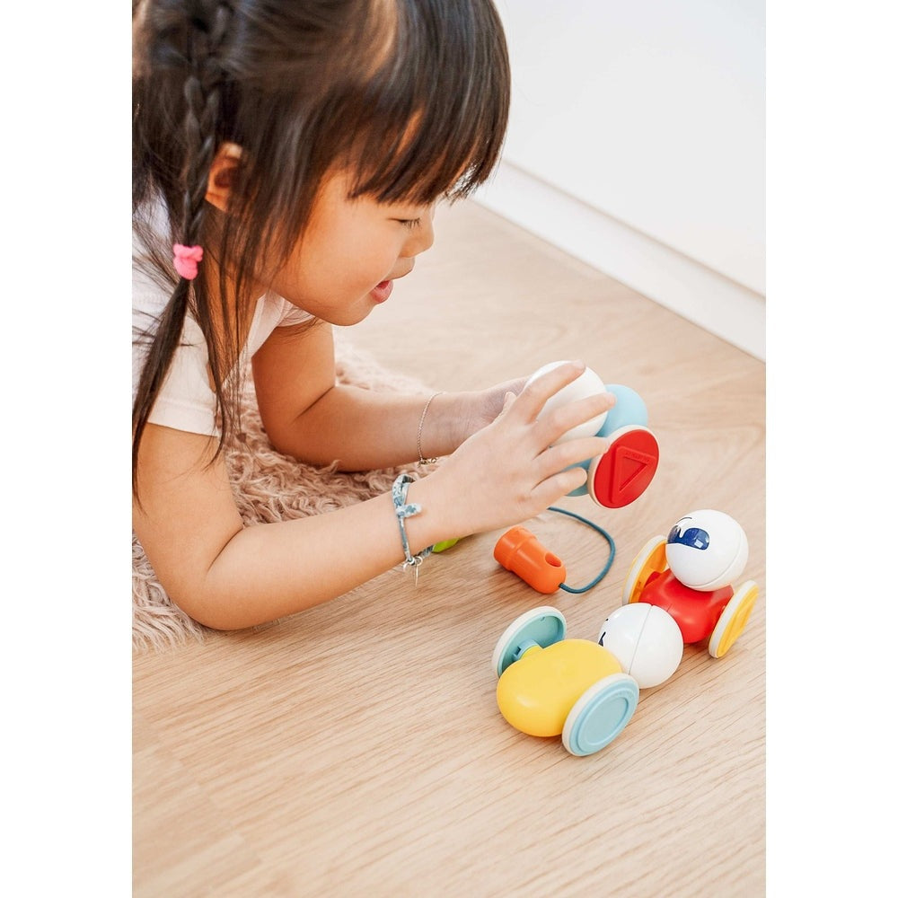 SmartMax My First Wobbly Cars magnetic toy set; colorful plastic cars with blue and yellow wheels beside a child.