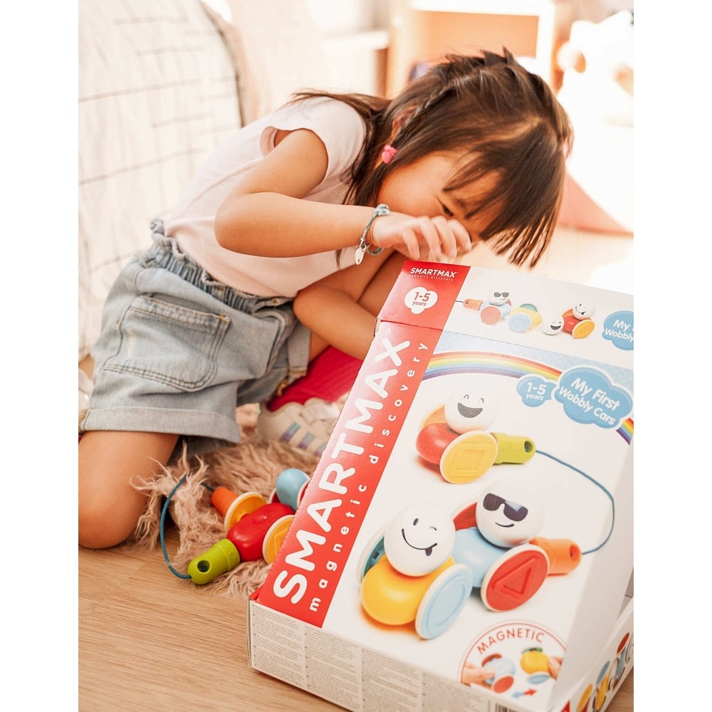 SMARTMAX My First Wobbly Cars magnetic toy kit with bright colors; young girl plays nearby