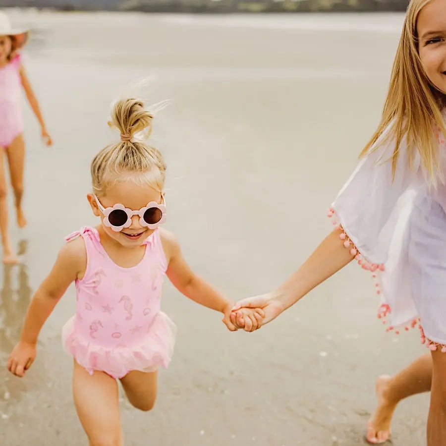 Snapper Rock Seahorse Sparkle Skirt Swimsuit pink toddler one-piece; girl runs on wet sand, tutu skirt fluttering.
