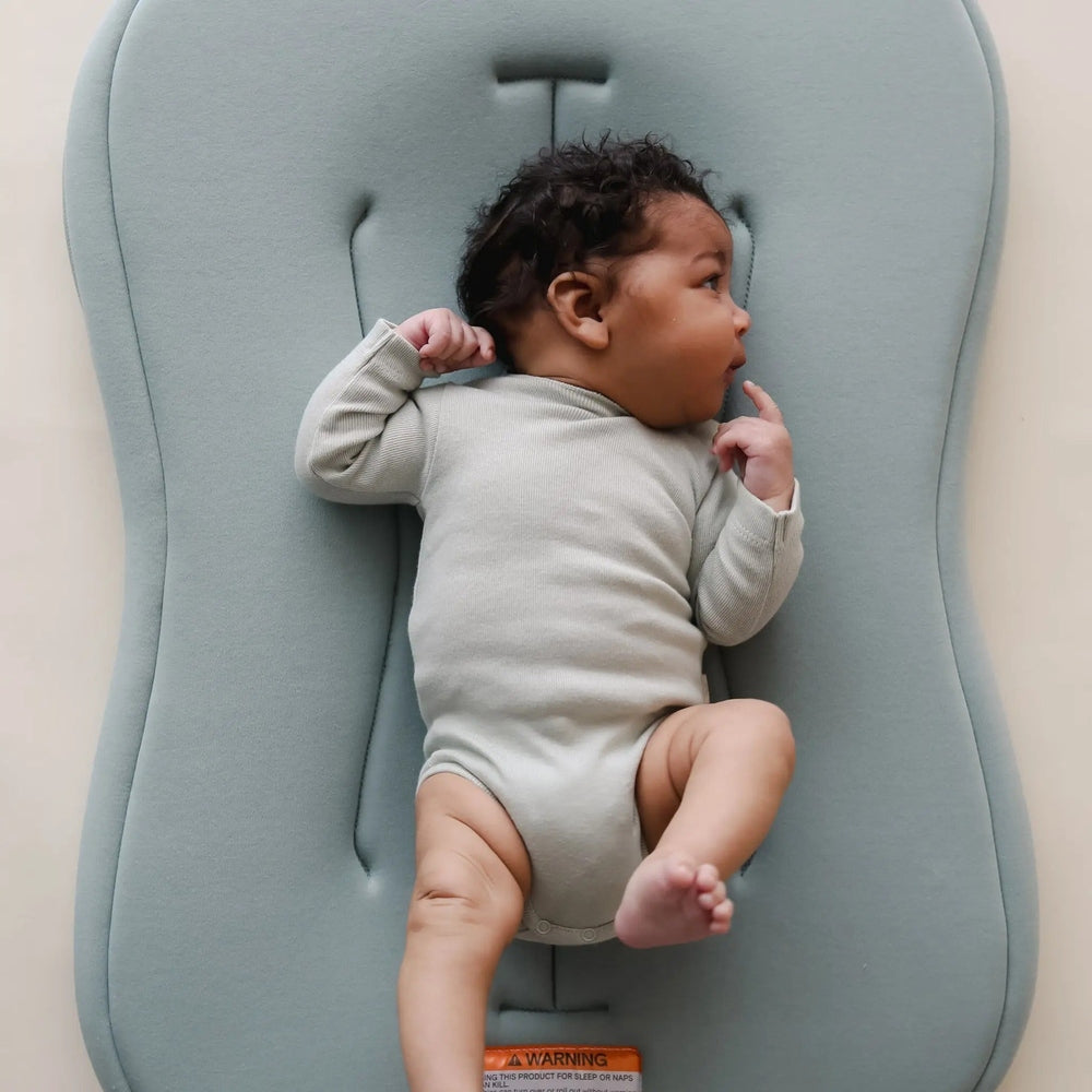 Snuggle Me Organic Lounger Curve baby resting on curved blue nursing lounger, plush fabric.