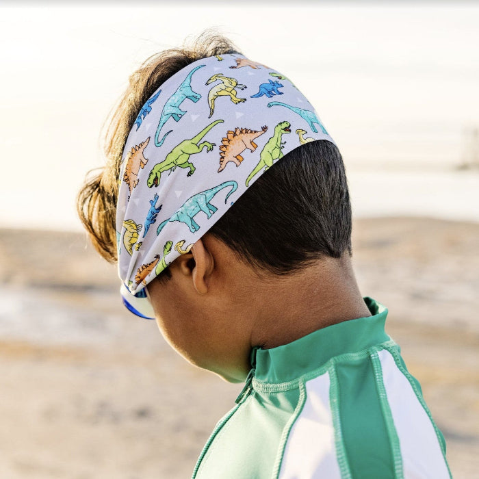 Splash Swim Goggles Dino headband on a child at the beach wearing a green rash guard.