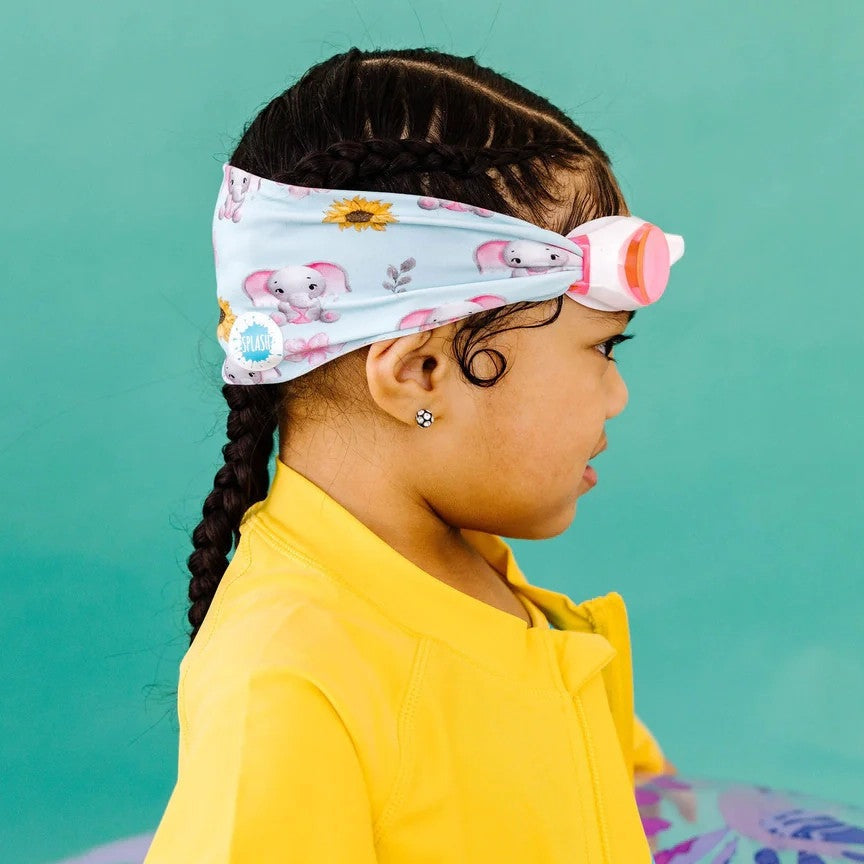 Splash Swim Goggles Ellie kids’ swimming goggles worn by a girl in a yellow shirt with a pastel elephant-print headband