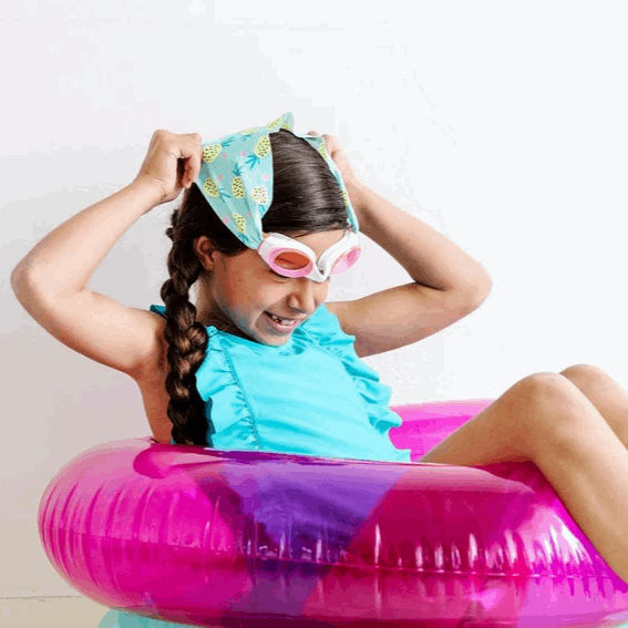 Splash Swim Goggles Pineapple Crush for kids; pink-framed goggles, pineapple-print headband, blue swimsuit, pink float.