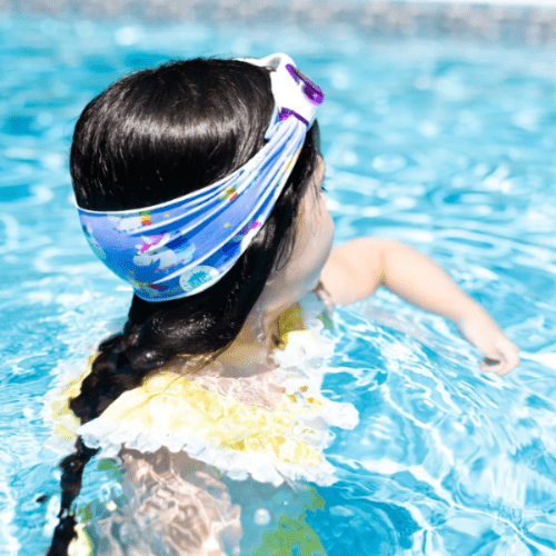 Splash Swim Goggles Rainbow Unicorn, blue unicorn-pattern goggles with matching headband worn by a child in the pool