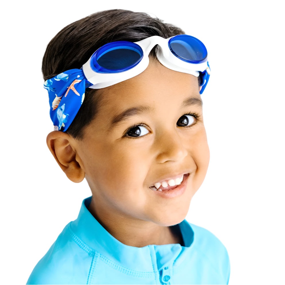 Splash Swim Goggles blue lenses and white frame worn by a child in a bright blue shirt with sea-themed headband
