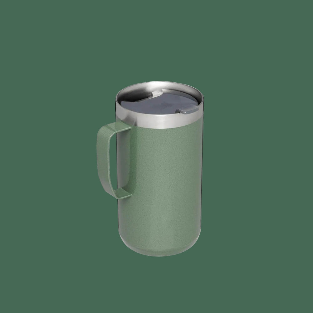 Stanley Classic Stay-Hot Camp Mug 24 oz, green steel with metal lid, held upright by its sturdy handle.