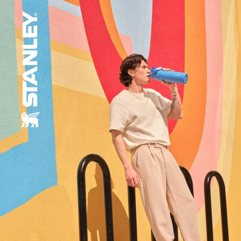 Stanley IceFlow Flip Straw 2.0 20 oz tumbler in blue, shown against a colorful mural backdrop