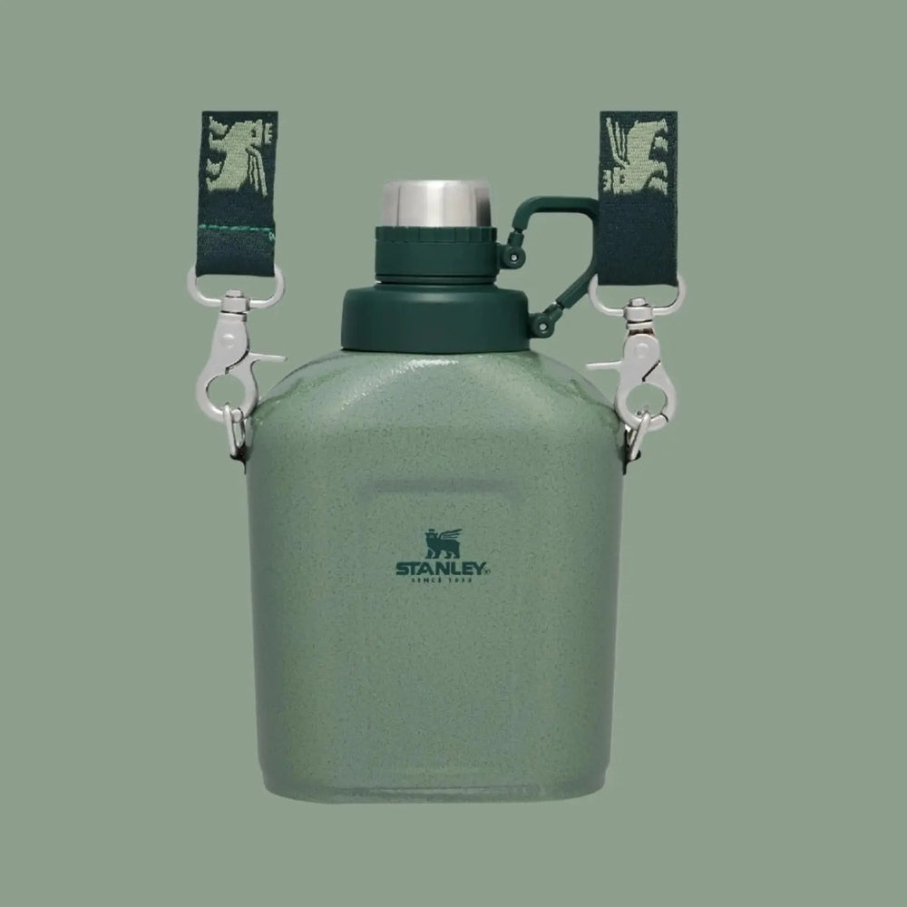 Stanley The Legendary Classic Canteen 1.1 Qt in green with dark cap; straps hooked to metal clips.