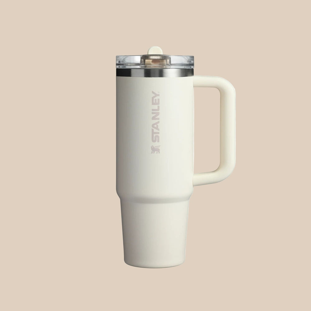 Stanley The Quencher Protour Flip Straw Tumbler 30 oz, cream with integrated handle, held by its side.