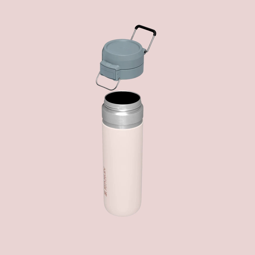 STANLEY The Quick Flip GO Bottle 24 oz with gray flip-top lid and attached carry handle on a pale pink bottle