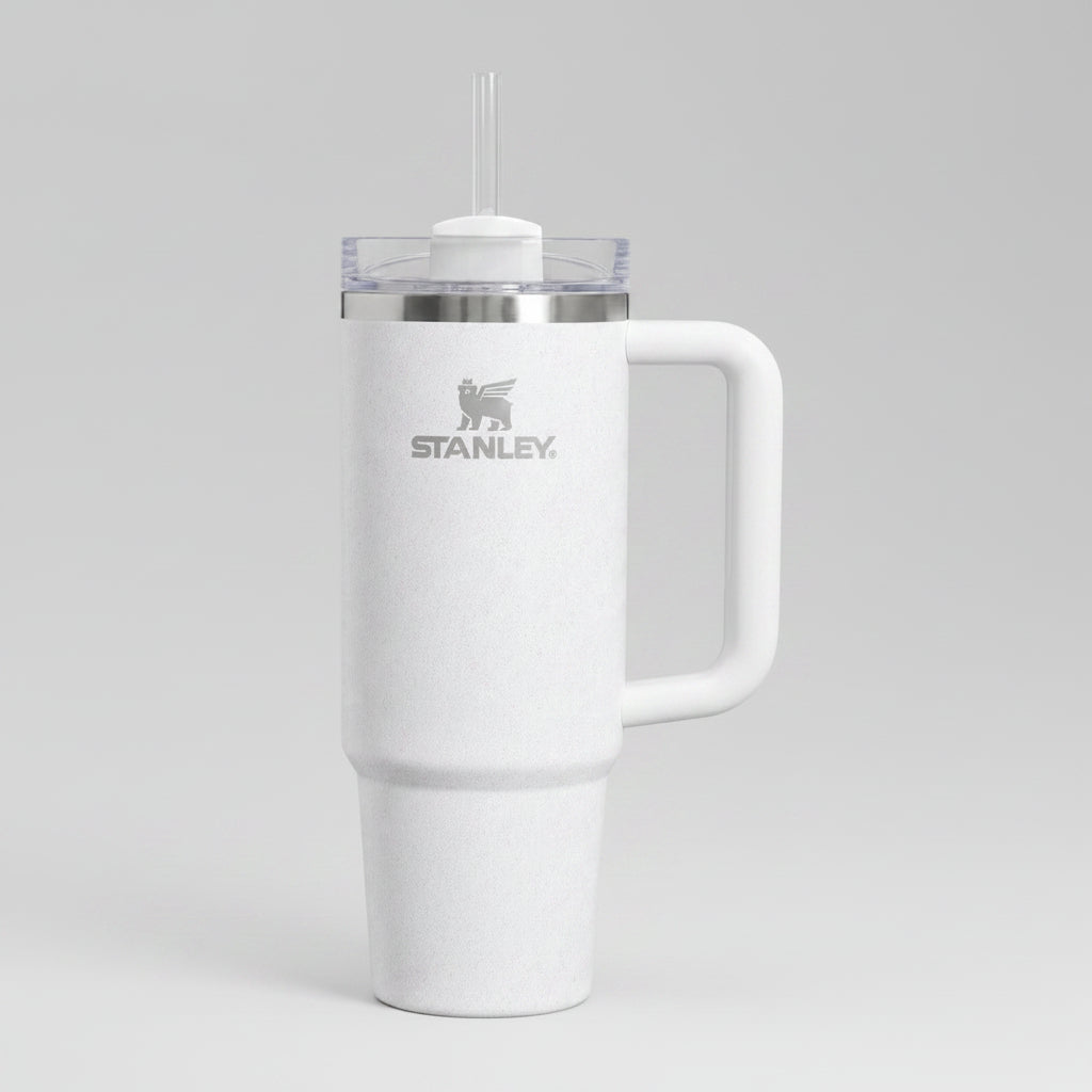A white Stanley vacuum-insulated tumbler with a handle, a clear lid, and a white straw, shown on a plain white background.