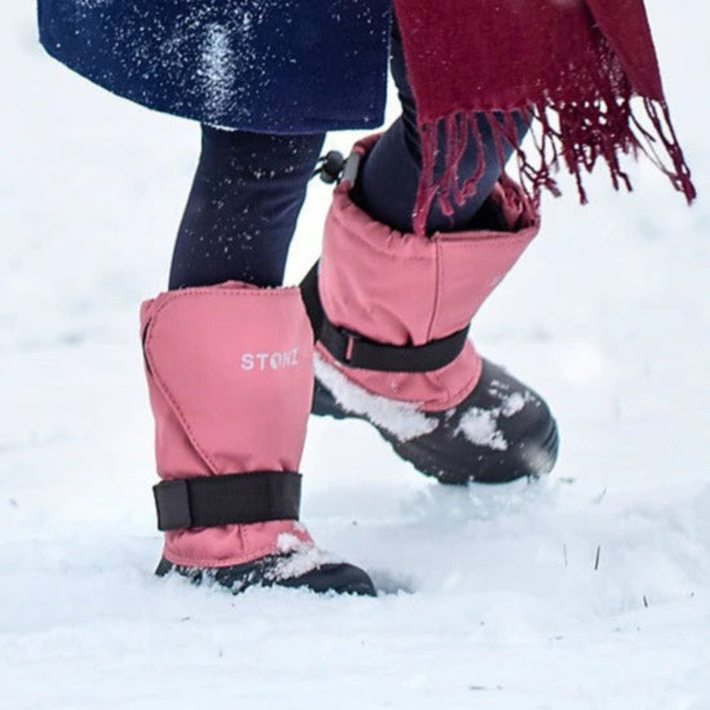 Stonz Trek Kid Snow Boots Dusty Rose, pink STONZ waterproof boots with straps, kid stomping through snow.