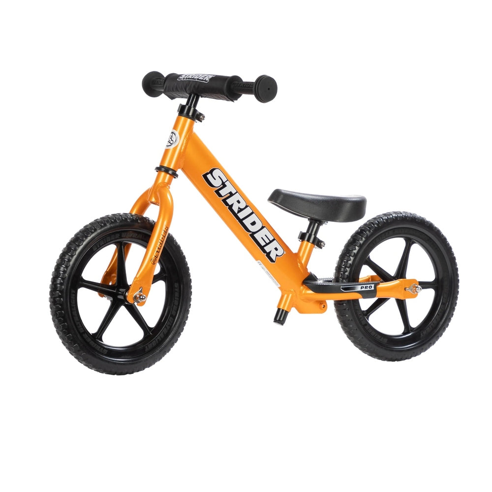 Strider 12 Pro Balance Bike in orange with lightweight aluminum frame, black 12-inch wheels, adjustable seat, and padded handlebars