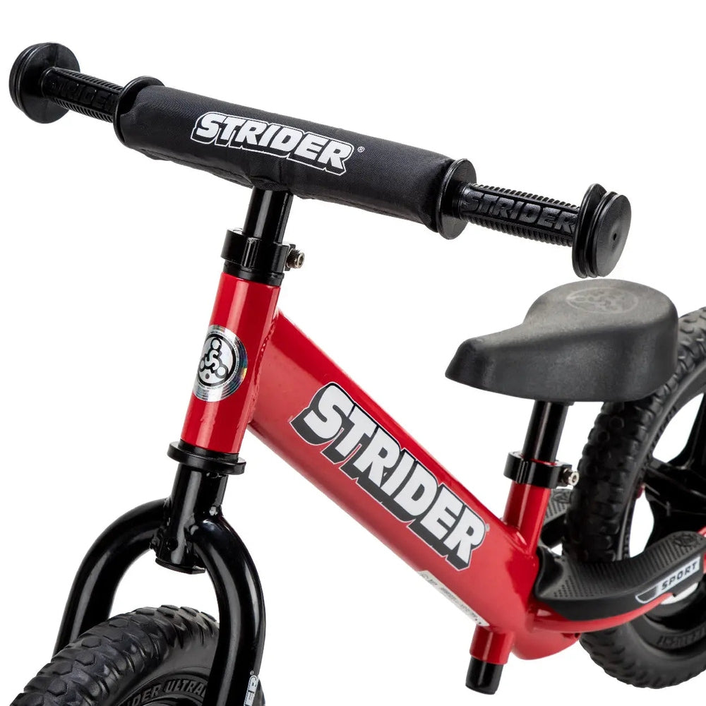 Strider 12 Sport Balance Bike, red frame with black padded handlebars, ready for first rides.