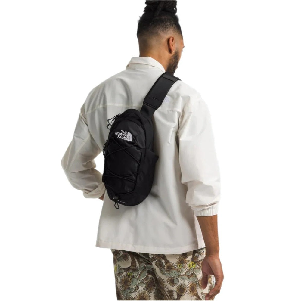 The North Face Borealis Sling Crossbody Bag in Black worn across the back by a person in a white shirt.