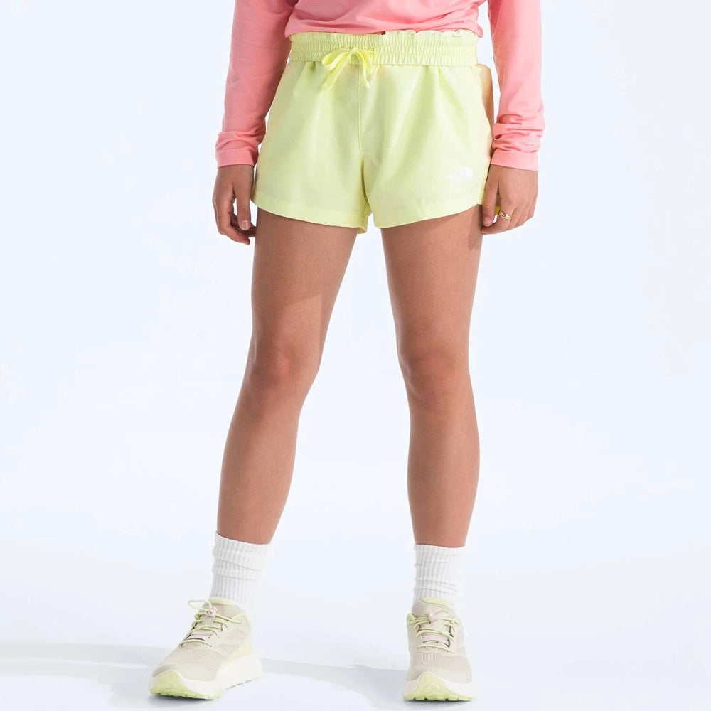 Person wearing light green shorts, pink long-sleeve top, and white sneakers on a white background