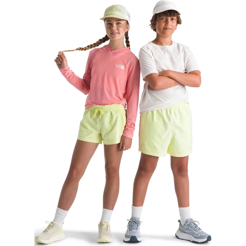 Two children wearing matching athletic outfits with pink and white tops and yellow shorts on a white background.
