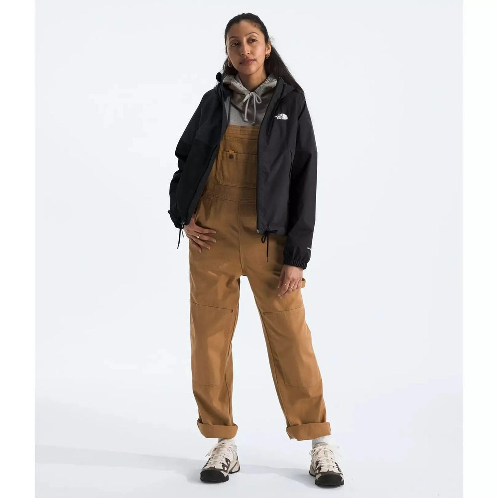 Person wearing brown overalls and a black jacket on a white background
