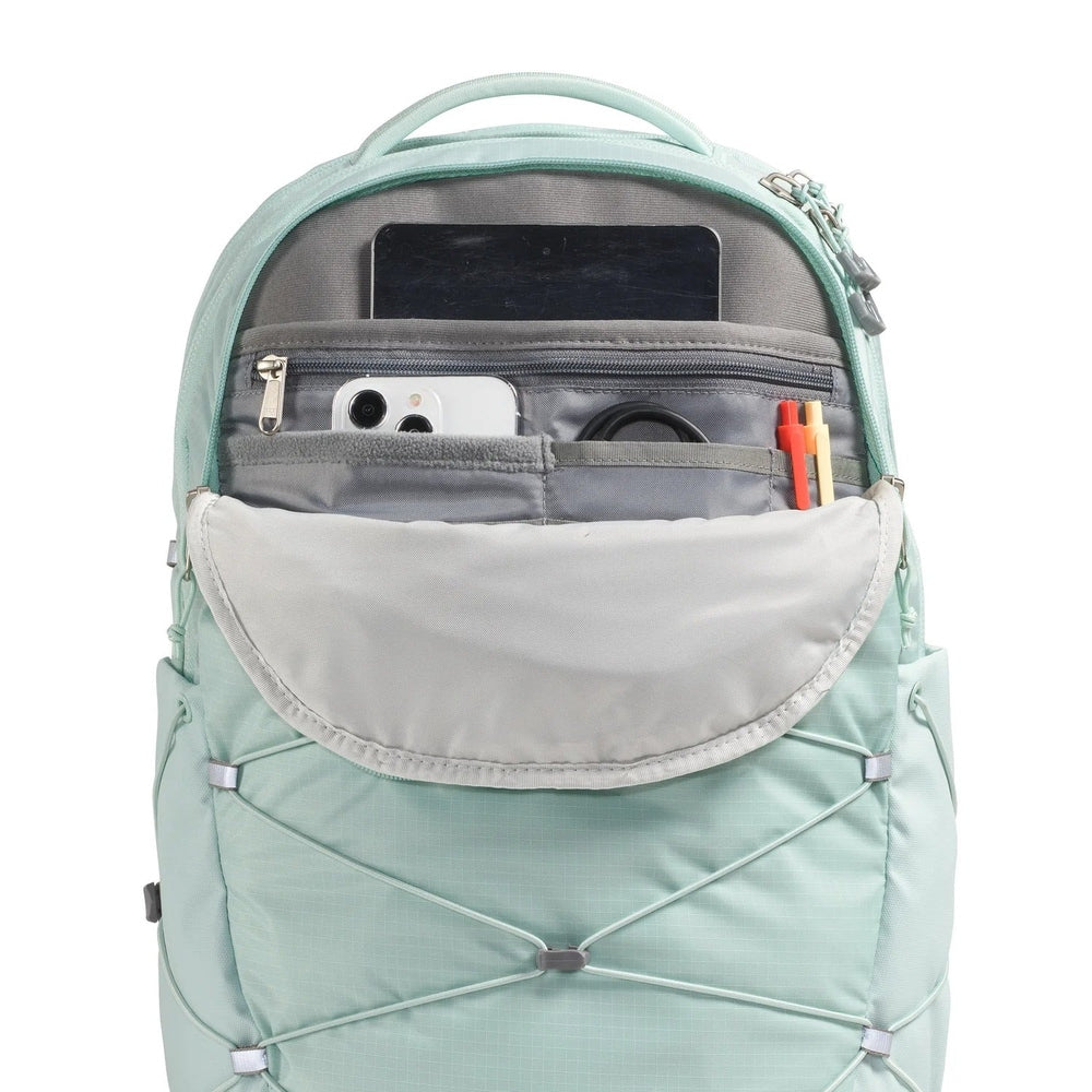 The North Face Borealis Backpack in Mint Green with grey front pocket open, showing phone and pencils, and bungee cords.