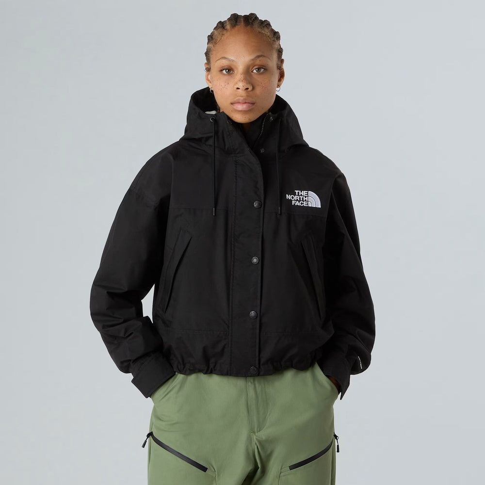 The North Face Women’s Reign On Jacket in black, hooded rain coat with snap buttons and chest logo.