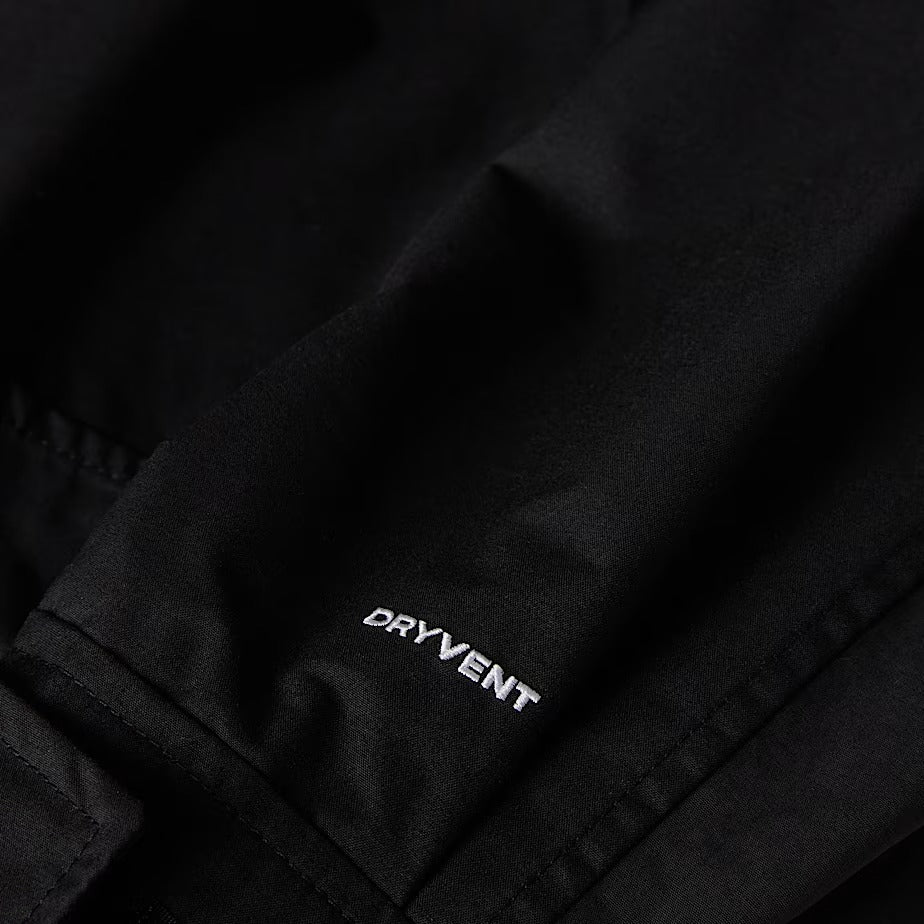 Black The North Face jacket sleeve close-up in DRYVENT fabric with white embroidered logo.