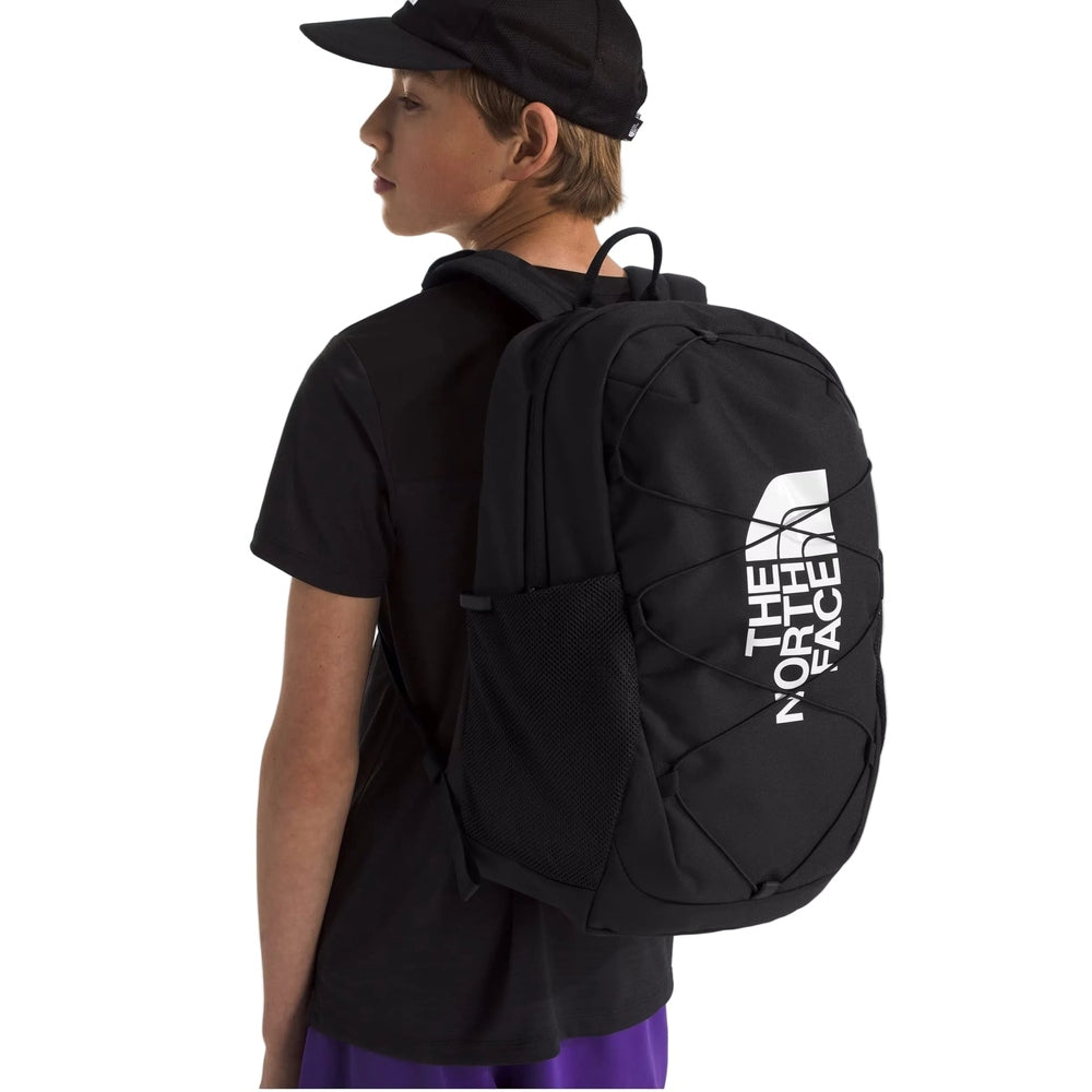 The North Face Youth Court Jester Backpack in Black with white TNF logo, front bungee cords, and side mesh pocket.