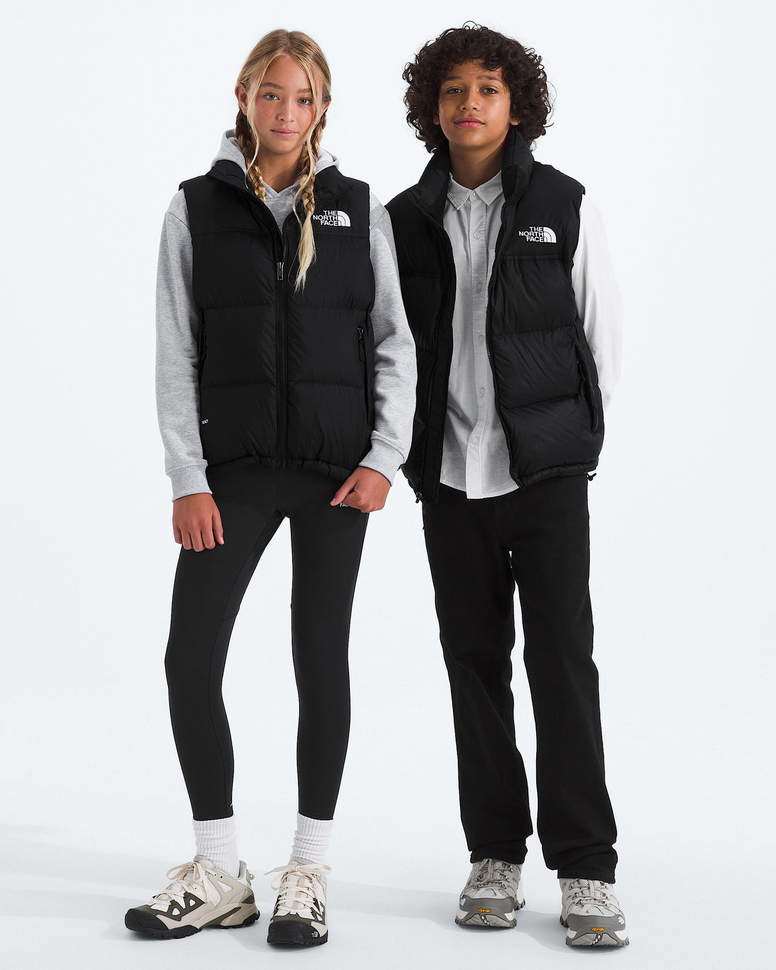 Two kids wearing The North Face 1996 Retro Nuptse Vest in TNF Black / Recycled Down, front view