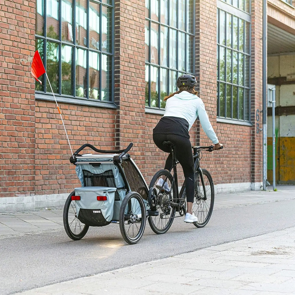 Thule Chariot Cross Multisport Bike Trailer Alaska Blue being towed by a cyclist along a city street