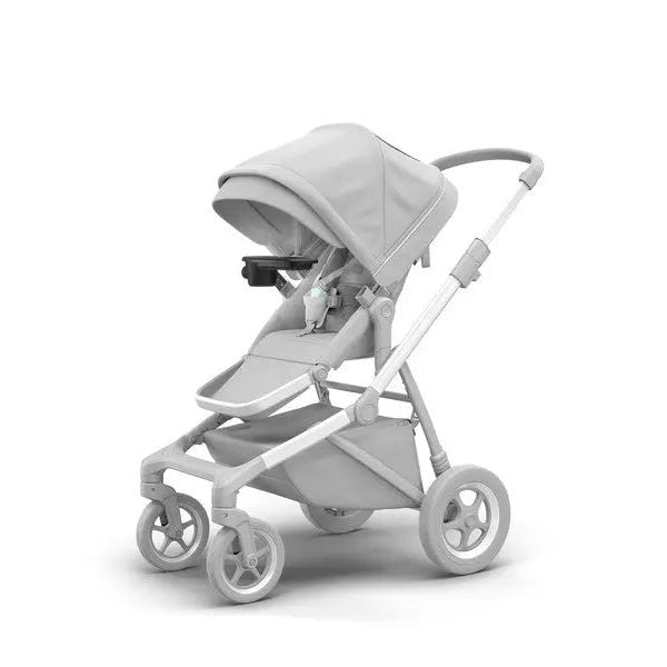 Thule Sleek Snack Tray attached to a gray stroller, featuring a cup holder and tray in use.
