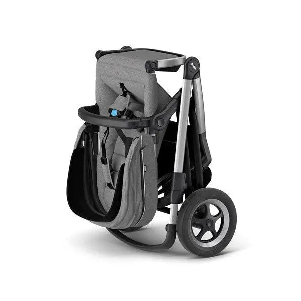 Thule Sleek Stroller in gray fabric with black frame, folded for compact storage, large rear wheels visible.