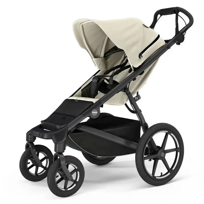 Thule Urban Glide 4-Wheel stroller in beige canopy and black frame; adjustable canopy and large wheels suggest all‑terrain use.
