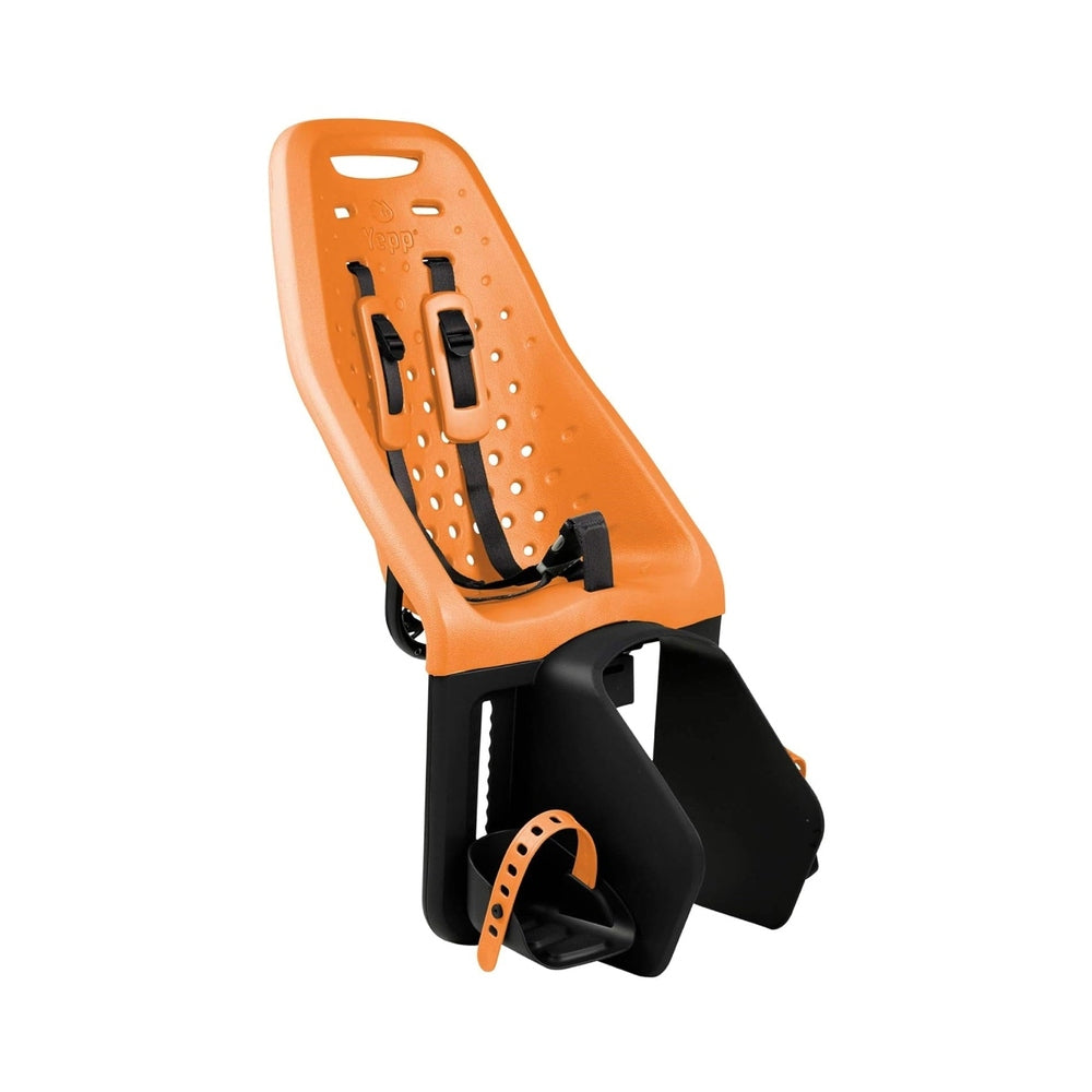 Thule Yepp Maxi rack-mounted child bike seat in orange with black harness straps secured to a bike rack.