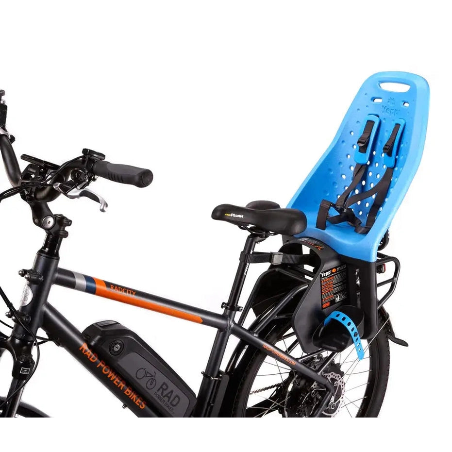 Thule Yepp Maxi rack-mounted child bike seat in blue securely attached to rear of a black Rad Power bike with harness.