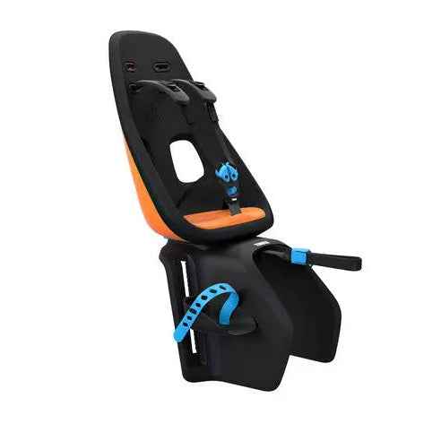 Thule Yepp Nexxt Maxi child bike seat in black with orange padding, mounted securely on a trailer frame.
