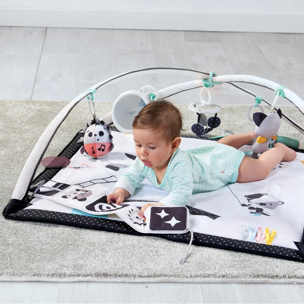 Tiny Love Magical Tales Black & White Gymini play mat with arch, baby on tummy reaching for attached toys.