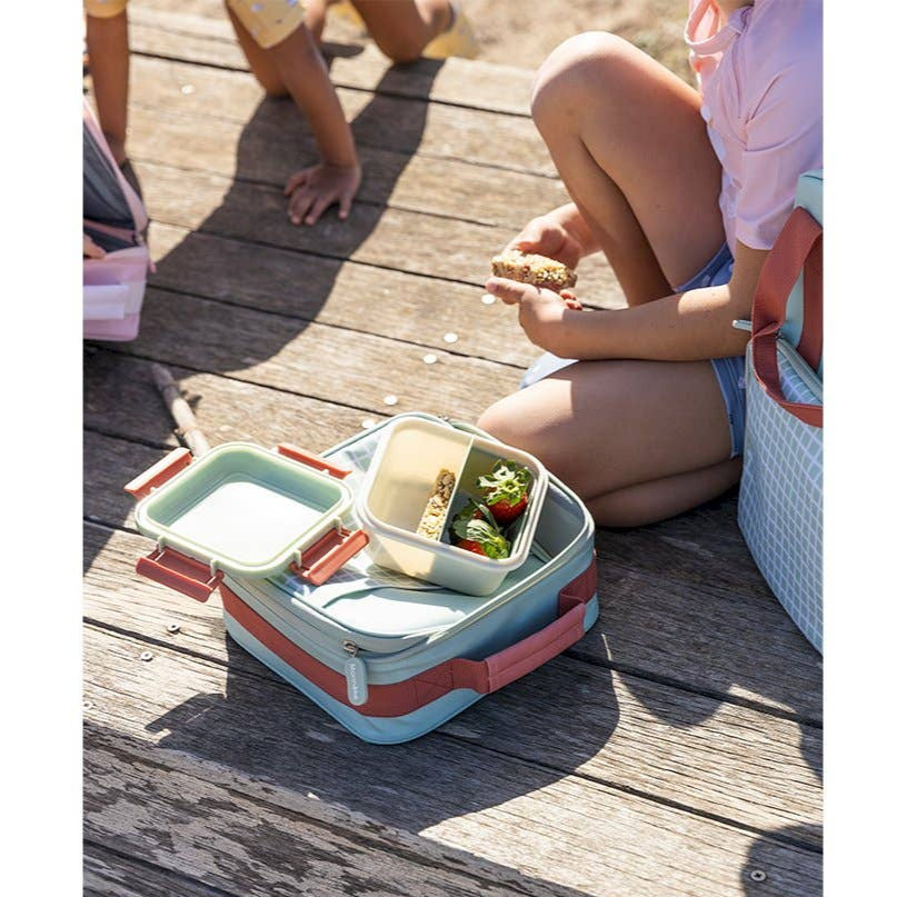 Tutete large lunch box, pastel blue with pink accents, open to reveal two-tier containers on a wooden deck