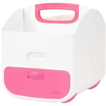 Ubbi Diaper Caddy white with pink handle and front panel, sits ready to organize baby essentials on a dresser.