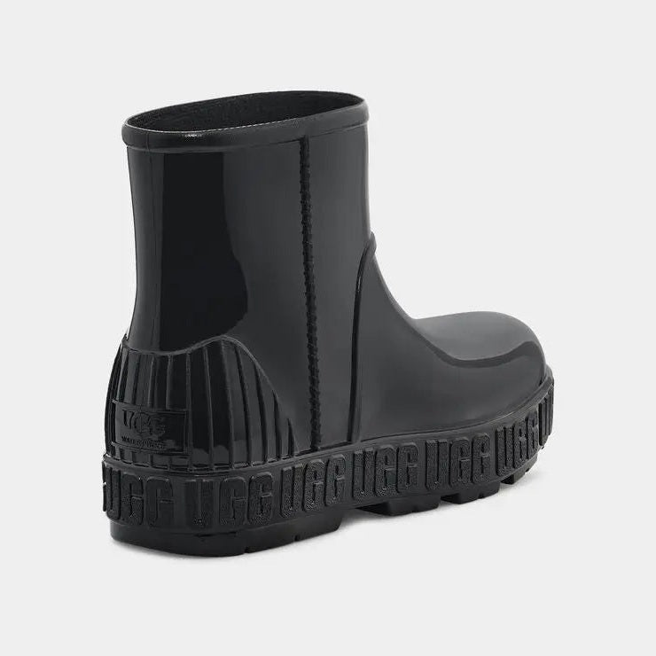 UGG Kid's Drizlita Black waterproof boot with glossy black rubber upper and chunky tread sole (rear view).