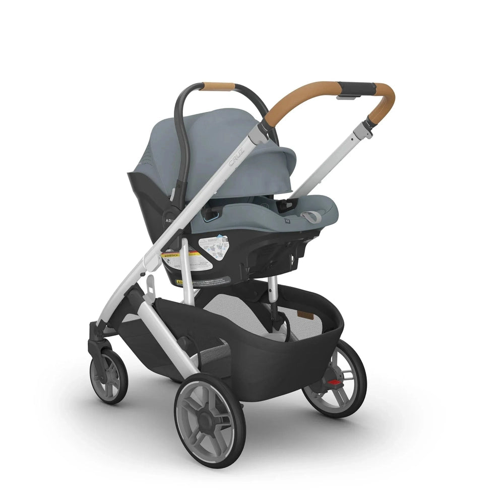 Uppababy Aria V2 Car Seat in Slate Blue mounted on silver stroller frame with tan leather handle.