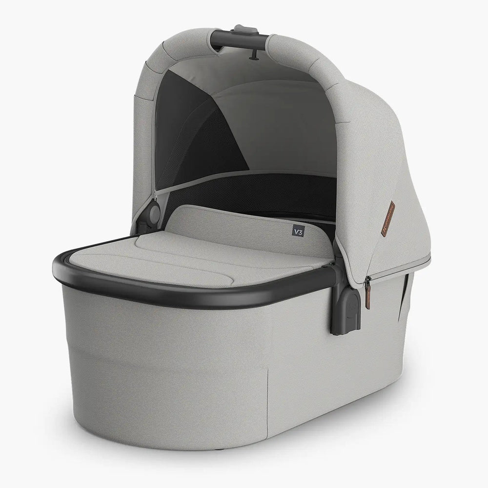 UPPABaby Bassinet V3 in gray fabric with protective canopy, showing the wide, padded bassinet surface ready for a newborn.