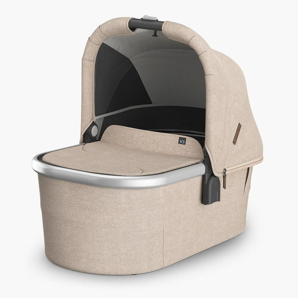 UPPABABY Uppababy Bassinet V3 in beige fabric with hood raised over the bassinet and a silver rim.