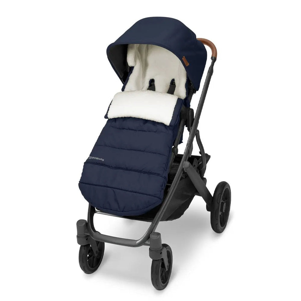UPPABABY Cozy Ganoosh navy footmuff with white sherpa lining attached to a stroller, keeping baby warm on walks.