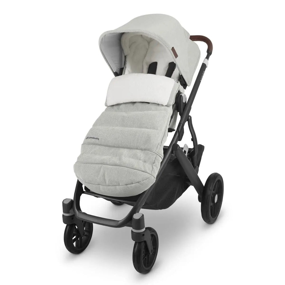 Uppababy Cozy Ganoosh footmuff in light grey attached to a stroller, keeping baby cozy in chilly weather.
