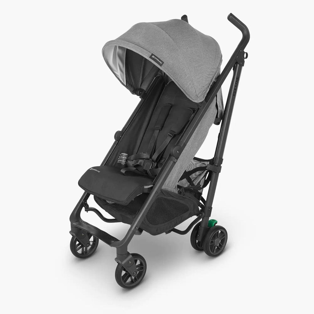 Uppababy G-Luxe Stroller in gray fabric with canopy, being pushed on a 4-wheel chassis.