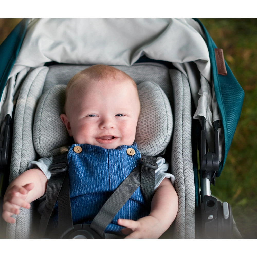 UPPAbaby Infant Snugseat in stroller with a smiling newborn in blue denim overalls