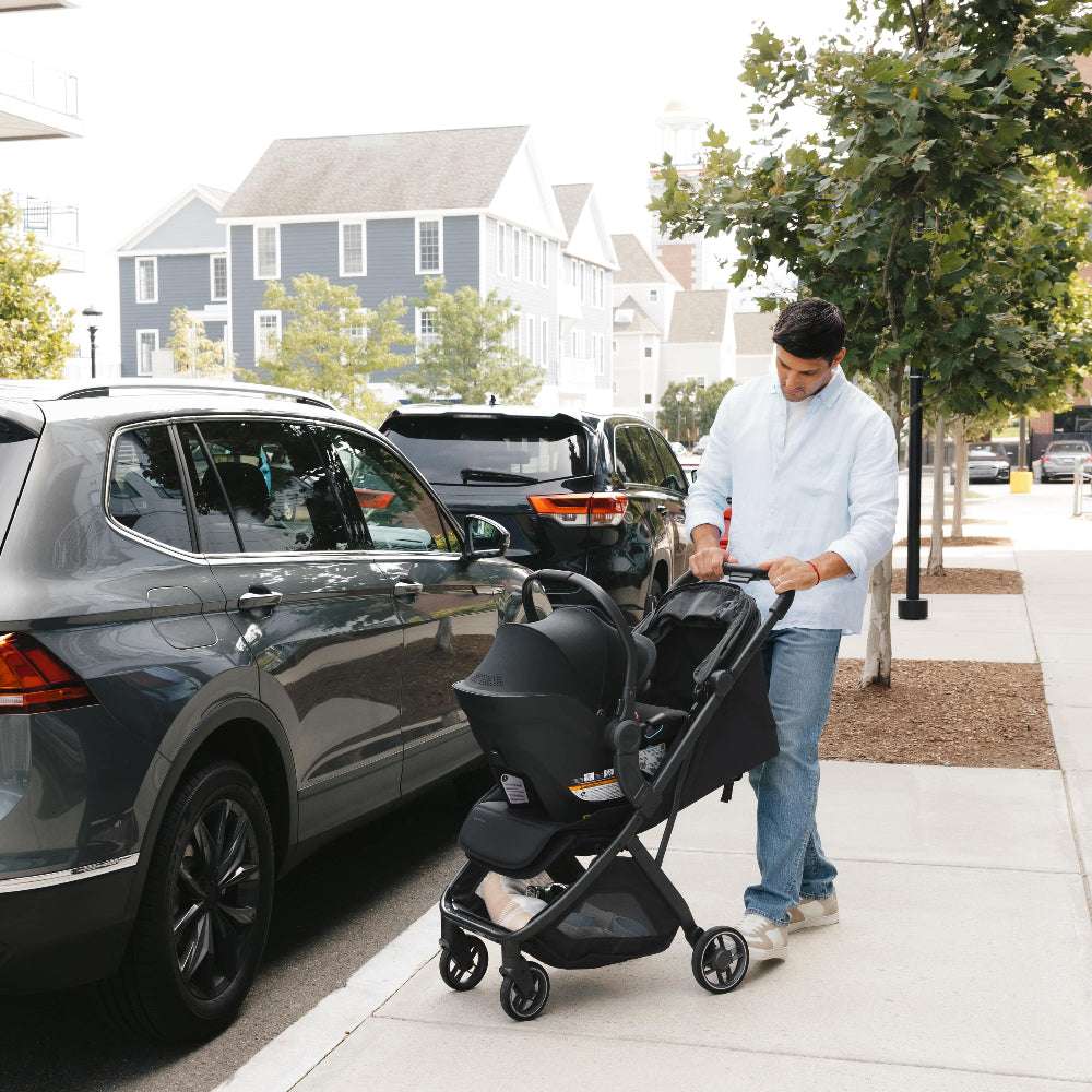 Uppababy Minu V3 stroller with black chassis being pushed along a sidewalk.