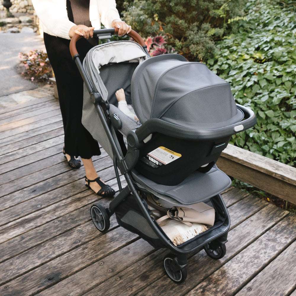 Uppababy Minu V3 stroller with gray bassinet on a wooden boardwalk