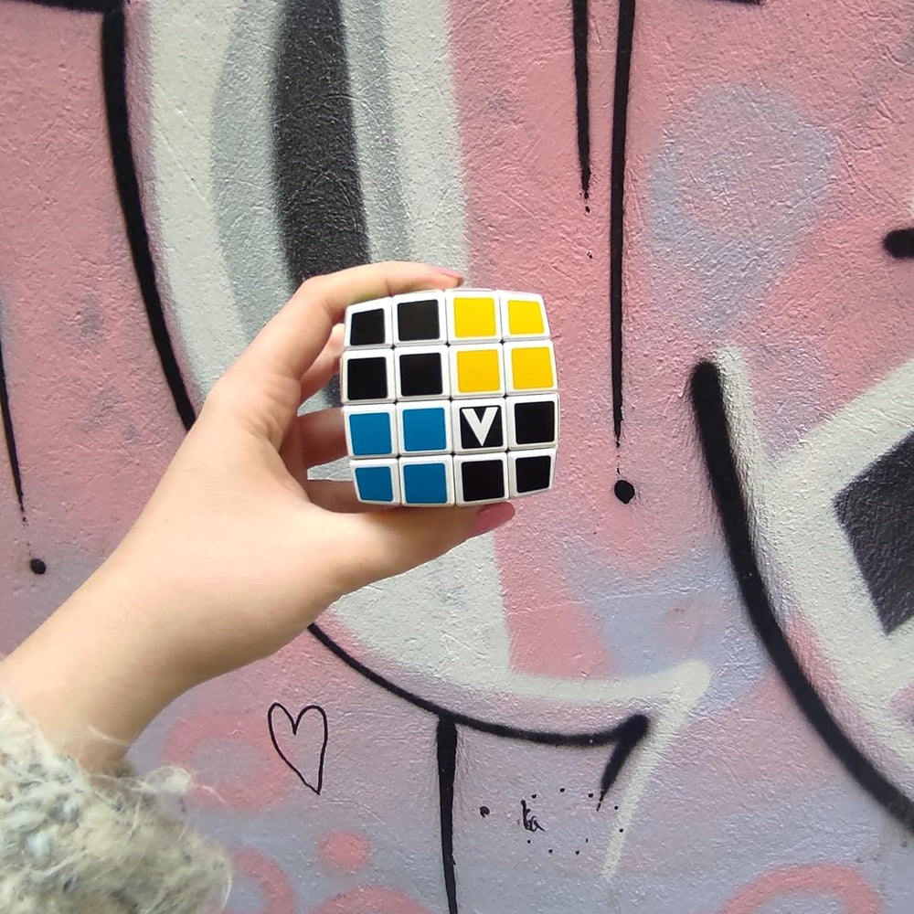 V-Cube 4x4 curved color-matching puzzle; white cube with blue, yellow, black stickers held in hand