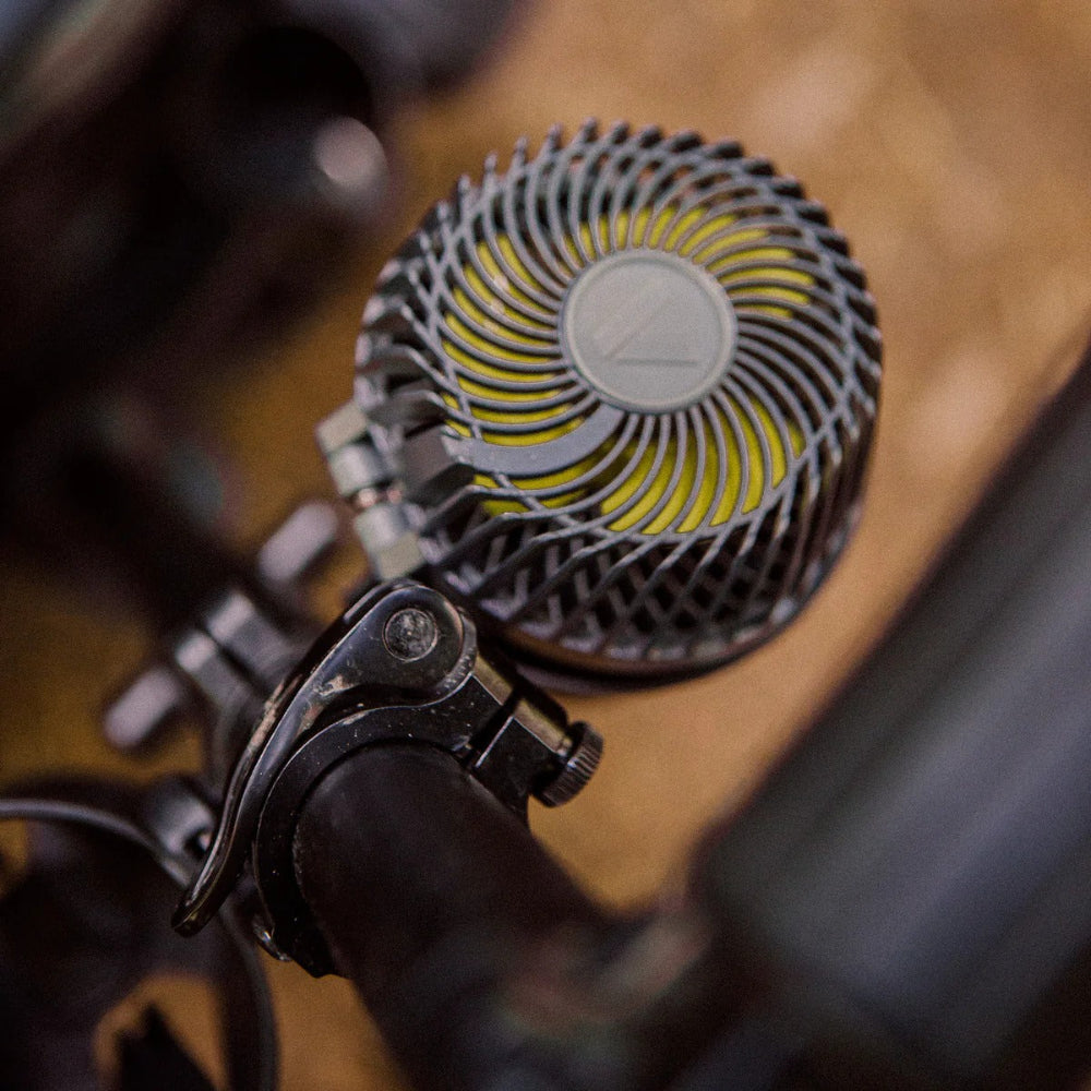 Veer Misting Fan mounted on a bicycle handlebar; compact gray unit with yellow blades.