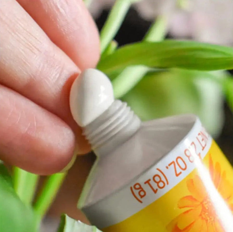 Weleda Calendula Diaper Cream 2.8 oz yellow-tube squeezed to a white dab on a fingertip.